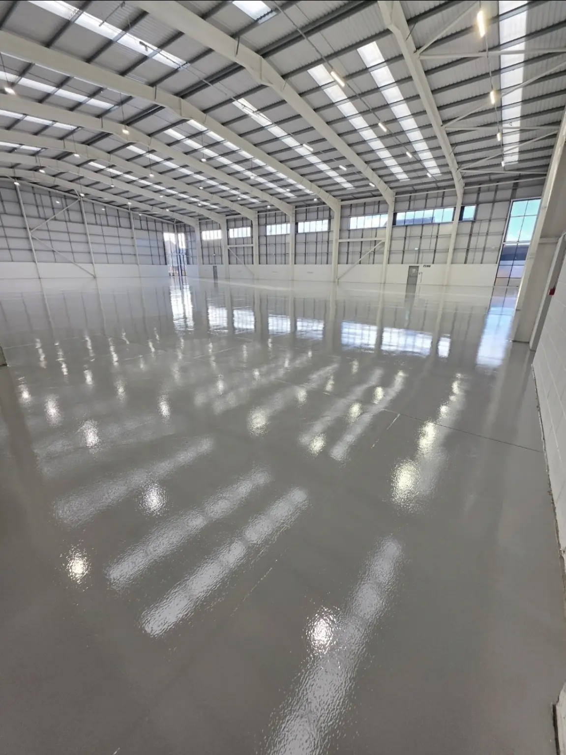 Completed warehouse epoxy floor showing reflective light grey finish