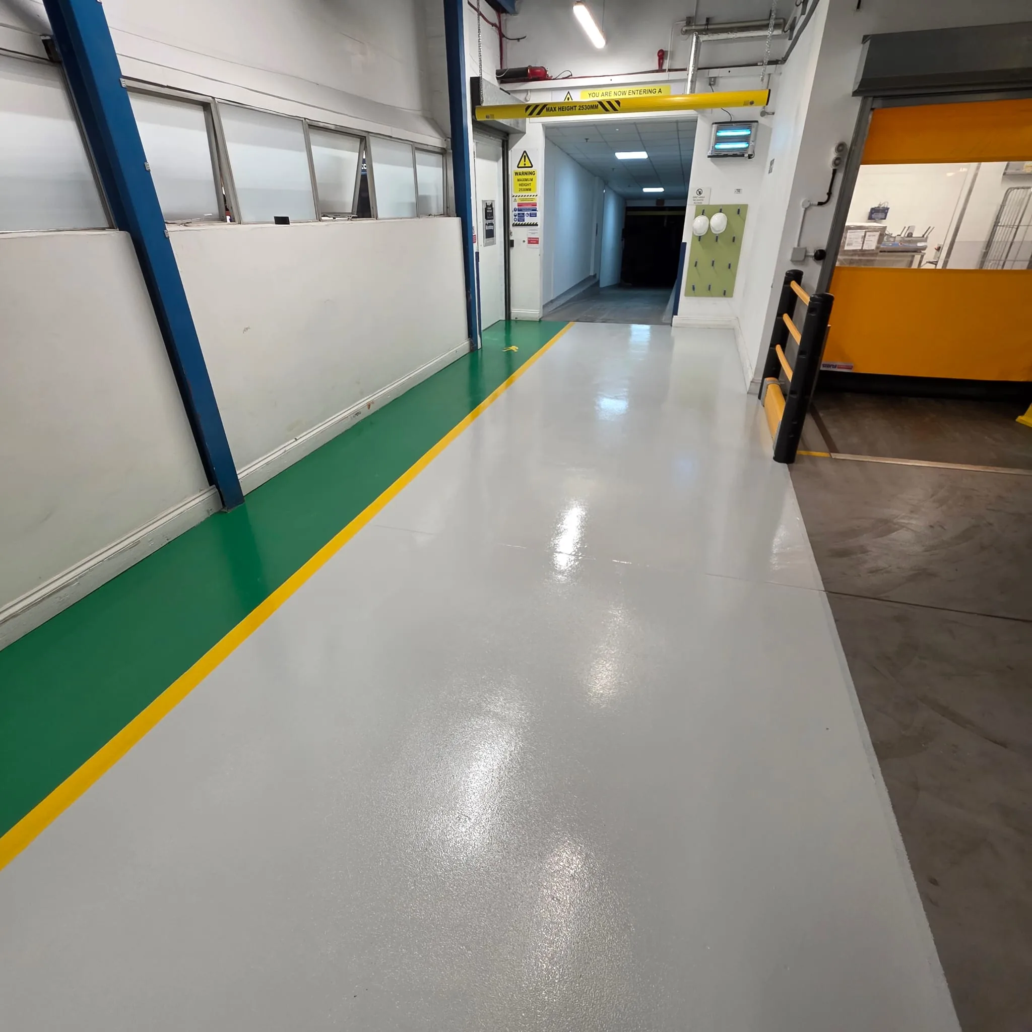 Factory floor with green pedestrian walkway, grey epoxy coating and yellow line marking