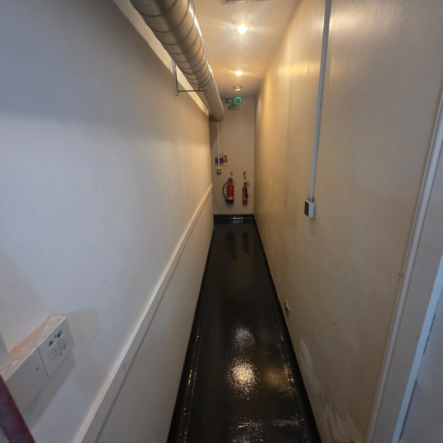 Dark resin flooring installed in narrow Novotel back-of-house corridor