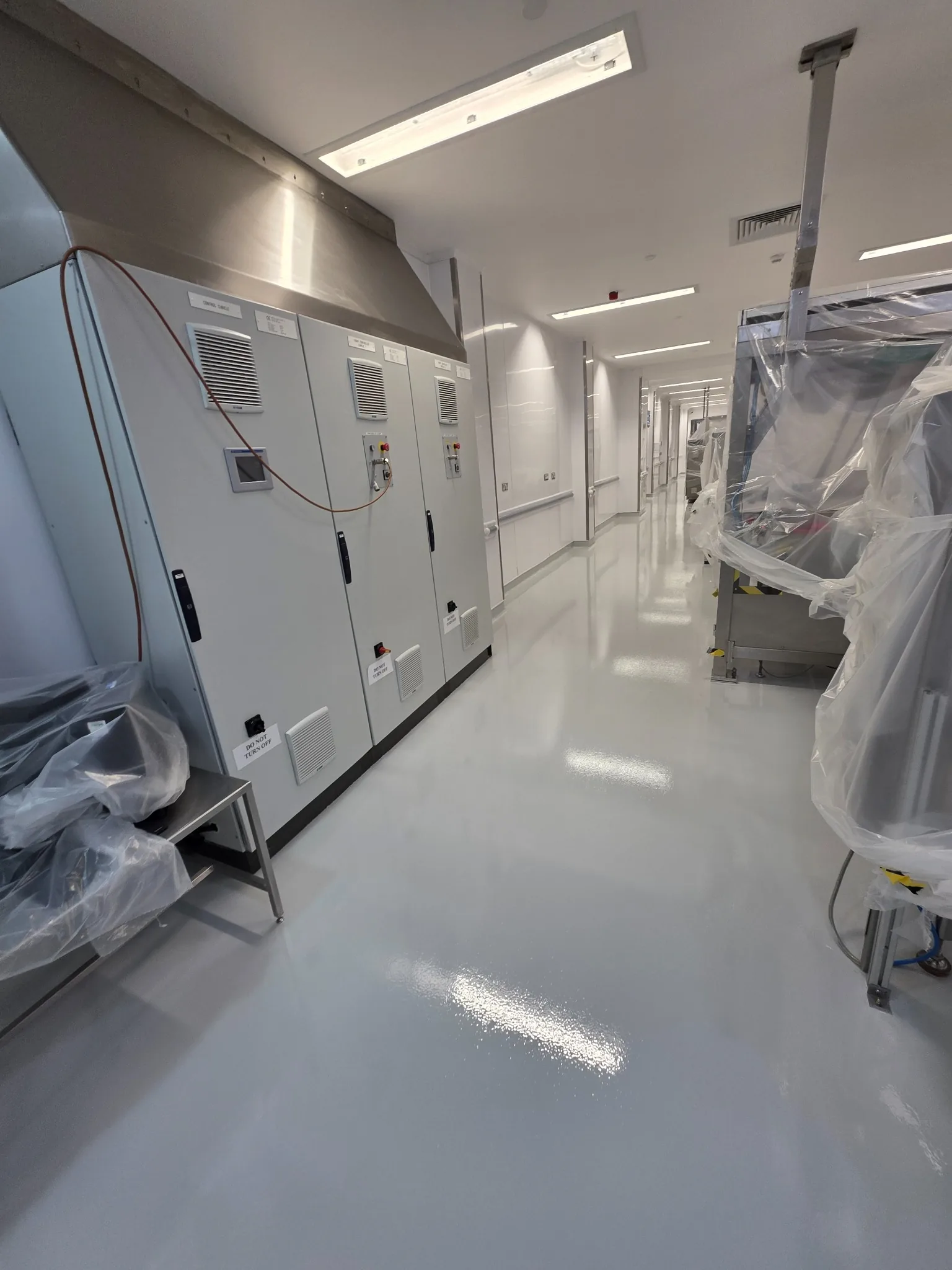 High-build epoxy flooring beside protected machinery in a pharmaceutical production corridor