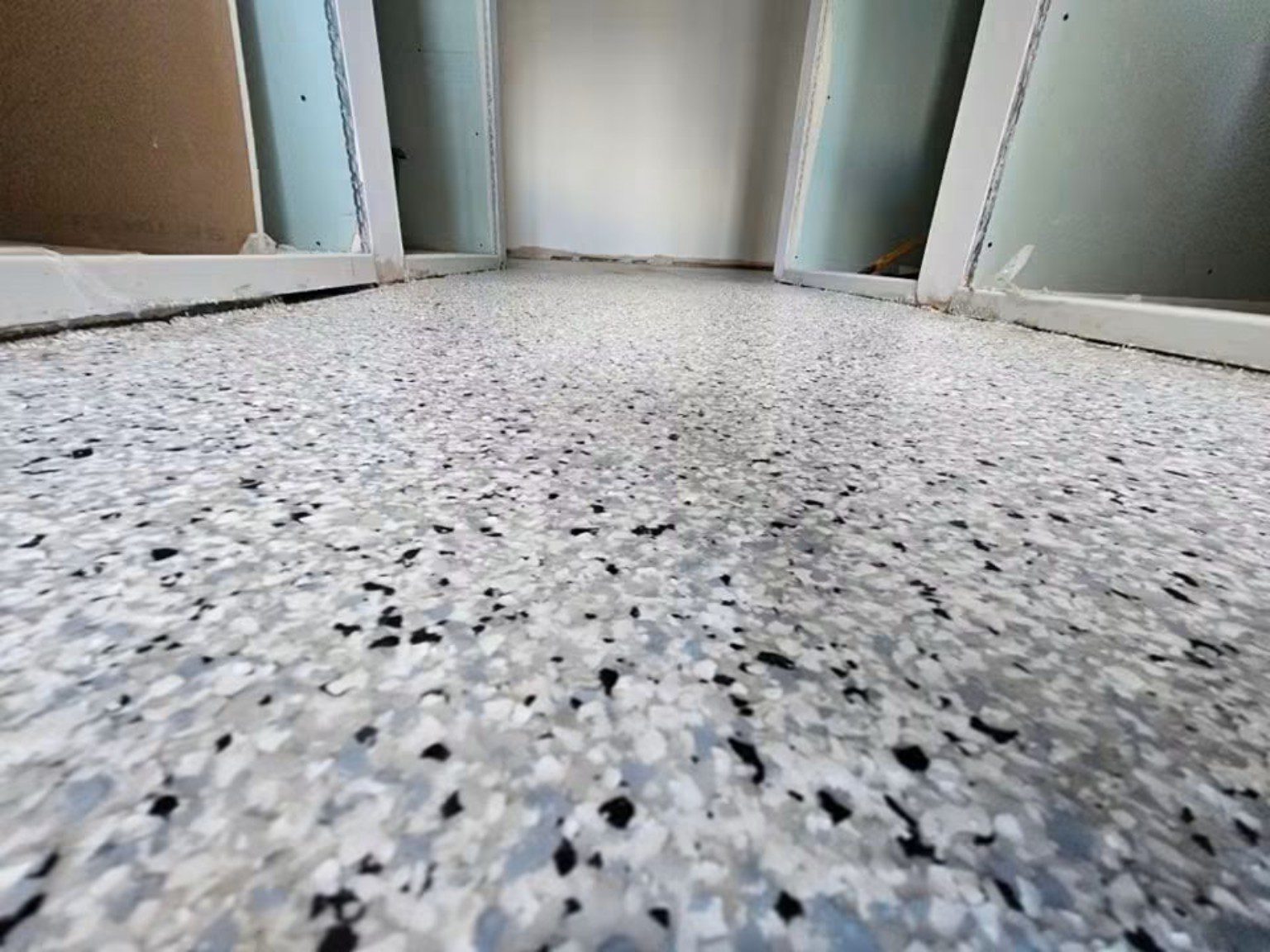 Grey speckled MMA resin flooring installed across a commercial room in Cardiff, viewed from floor level.